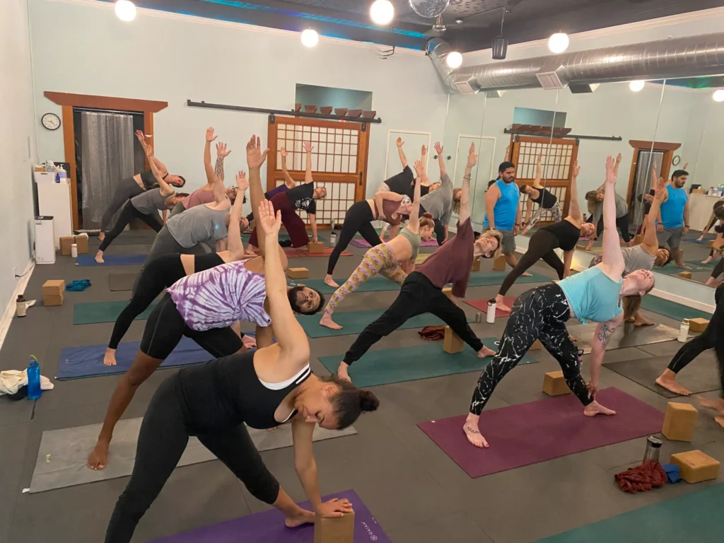 Yoga class mid-pose, participants leaning in triangle posture