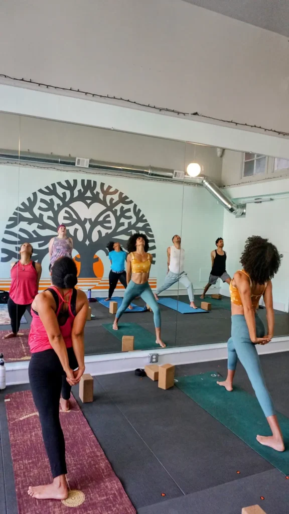 Small yoga class stretching in front of mirror and wall art
